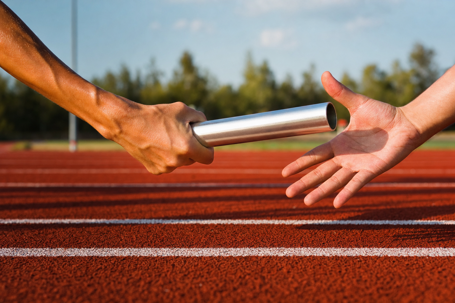 A physical relay-race baton being passed between two hands over a running track lane, symbolizing handing off marketing tasks