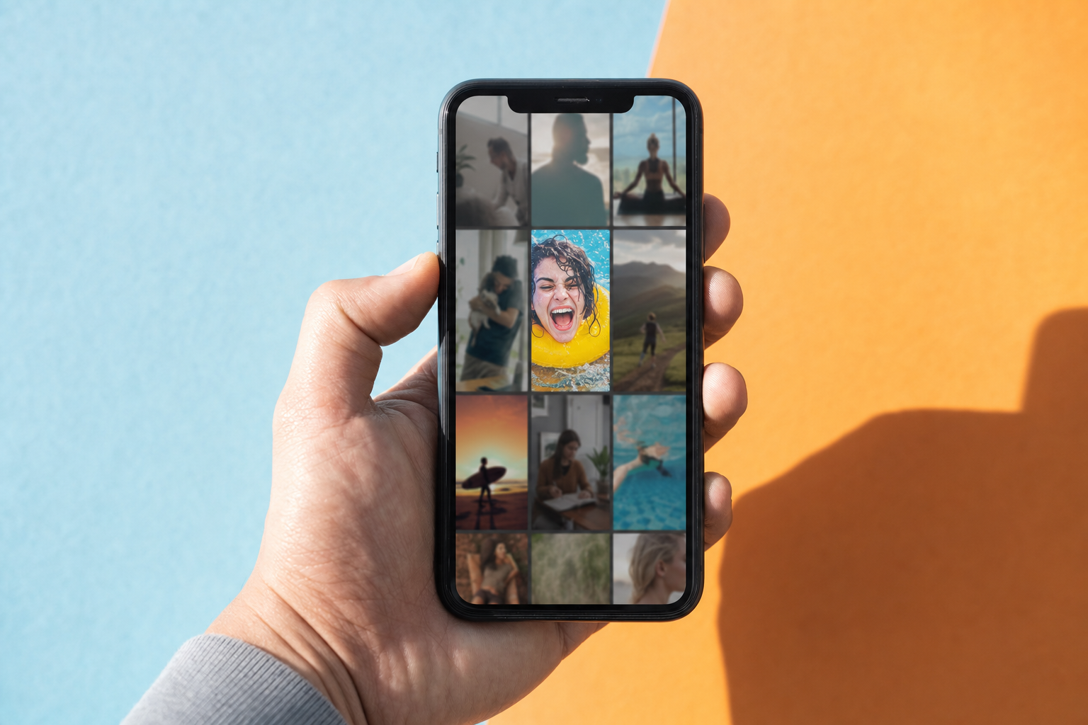 A hand holding a smartphone displaying a grid of colorful short-form video thumbnail options, with one high-contrast image standing out